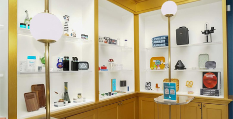 A variety of modern gadgets and accessories displayed on white shelves in a well-lit store with wooden accents.