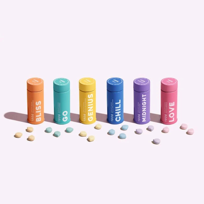 Six colorful supplement tubes labeled Bliss, Go, Genius, Chill, Midnight, and Love, with matching tablets in front.