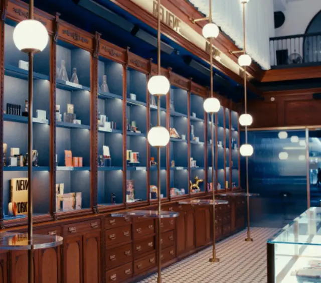 Elegant store interior with wooden shelves, globe lights, and various products displayed neatly on blue-lit shelves.
