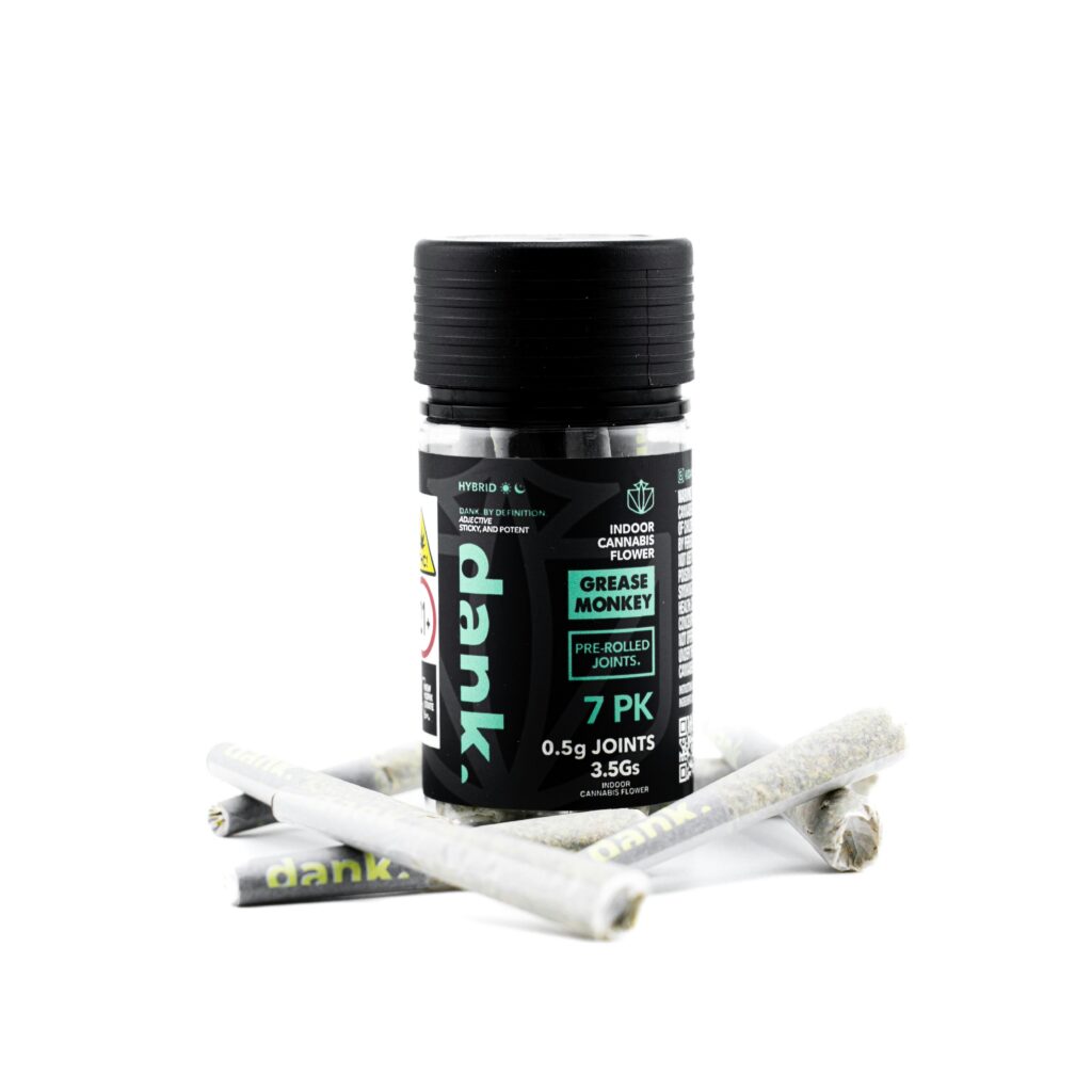 A black container labeled Grease Monkey 7 PK with several pre-rolled joints lying in front of it.