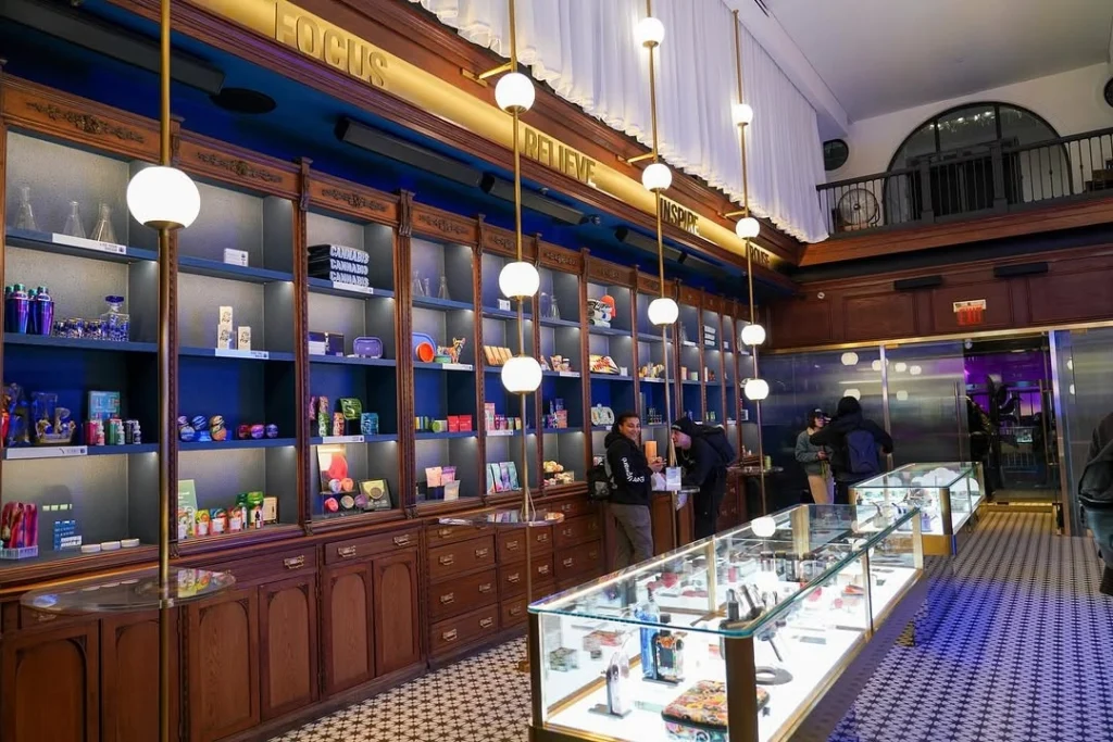 A modern cannabis store with glass display cases and shelves filled with colorful products, and people browsing inside.